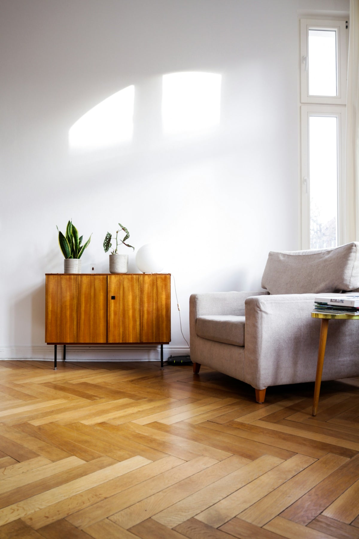 Sessel und Holzsideboard auf Fischgrätparkett im Altbau